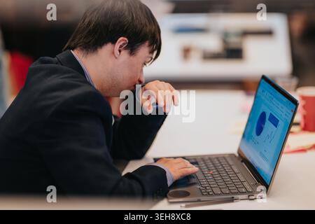 Young man working on laptop in business office reviewing charts and data Stock Photo