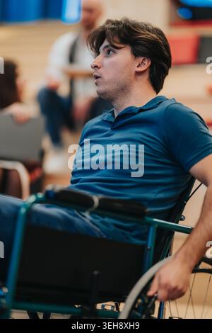Young man in wheelchair listening attentively during a college classroom discussion with peers Stock Photo