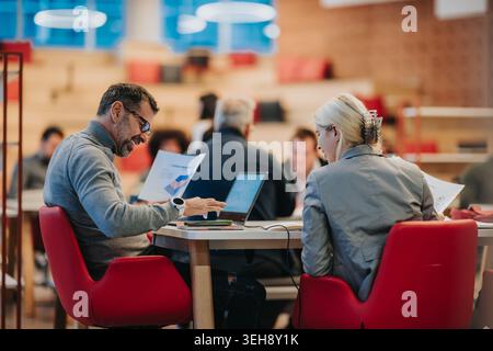 Business colleagues collaborating over laptop and documents in a modern coworking space during a meeting Stock Photo