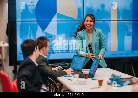 Confident businesswoman giving a presentation to a collaborative meeting with smiling team members Stock Photo