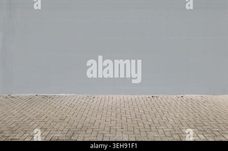 Light gray painted wall with concrete pavement in front. Background for copy space Stock Photo
