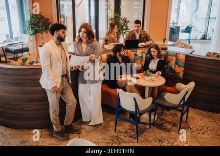 Business colleagues discussing documents in a casual coworking cafe during a collaborative meeting Stock Photo