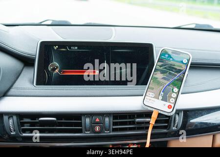 Digital dashboard of a premium automobile and mobile device with online GPS navigation during a ride. Smart vehicle electronics, gadgets for drivers Stock Photo