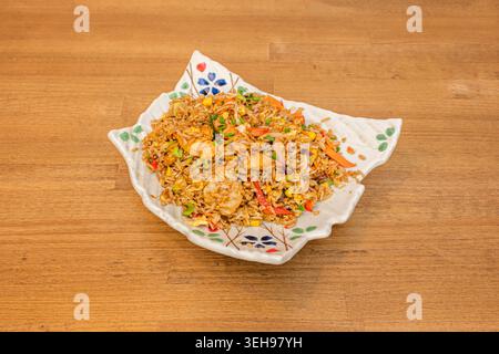 A close-up of Cantonese fried rice with generous pieces of char siu (roasted pork), baby prawns, peas, sweetcorn, and fresh spring onions, all with th Stock Photo
