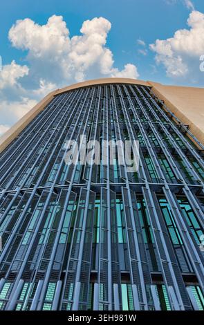 vertical perspective of a contemporary building facade. The design features a repetitive pattern of vertical metallic fins and rectangular wire mesh p Stock Photo