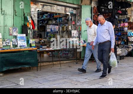 Jerusalem, Israel, May 20 2026,  Two elderly men walk past local shops on a stone-paved street in the Old City of Jerusalem. The man on the left wears Stock Photo
