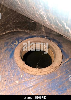 A threaded hole is visible in a water treatment cylinder showing dust and spider webs. This check takes place in a facility to ensure proper operation Stock Photo