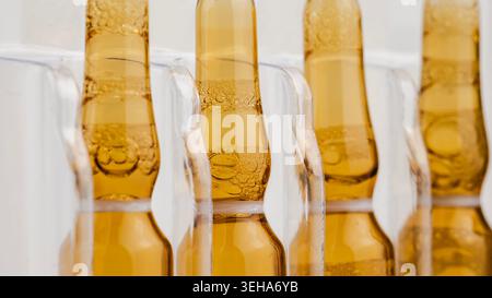 Macro shot of brown pharmaceutical ampoules with liquid vaccine and bubbles in a tray Stock Photo