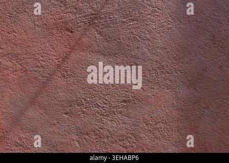 Textured plaster wall surface painted in a reddish brown terracotta color. Stock Photo