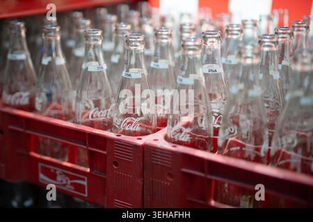 Reusable Coca-Cola bottles in Thailand, empty recycle glass bottles arranged in plastic boxes. Stock Photo
