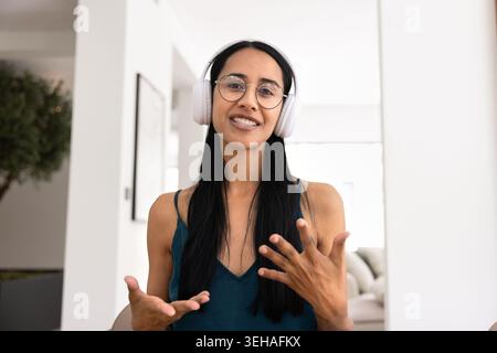Woman in headphones talking during online meeting Stock Photo