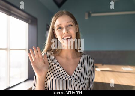 Caucasian woman wave hand at camera in office Stock Photo