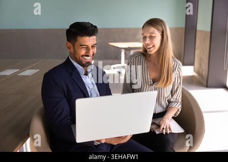 Two smiling coworkers collaborating on laptop in office Stock Photo