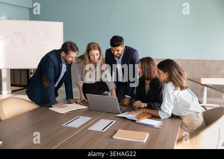 Group of diverse team members discussing online project on laptop Stock Photo
