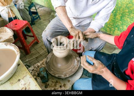 People Making Pottery with Focus on Spinning Potter’s Wheel and Clay Covered Hands at the Yeoju Ceramic Festival, South Korea Stock Photo