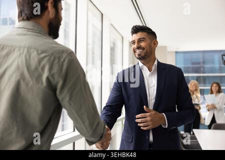 Two businessmen shaking hands in modern office Stock Photo
