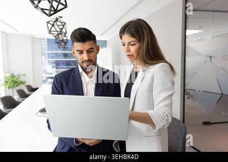 Focused colleagues using laptop in modern conference room Stock Photo
