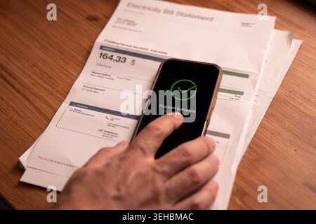 Close up of successful payment confirmation on smartphone over utility bill on table. Concept of online banking, financial solution, paid invoice and Stock Photo
