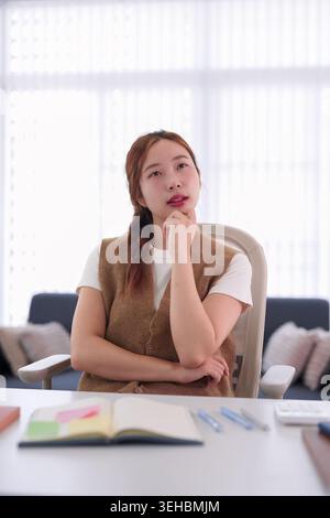 young Asian businesswoman thinking strategy solution planning project at office desk workplace business meeting room Stock Photo