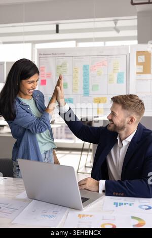 Two laughing workmates giving high five in office Stock Photo