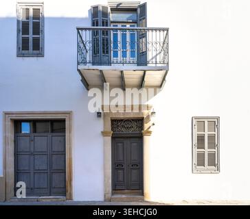 Larnaca, Cyprus. May 6 2026. A white building facade features multiple windows and doors. A balcony with decorative railing juts out from the upper st Stock Photo