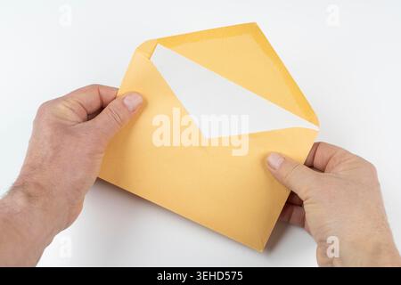 an open yellow envelope in the hands on a white surface Stock Photo