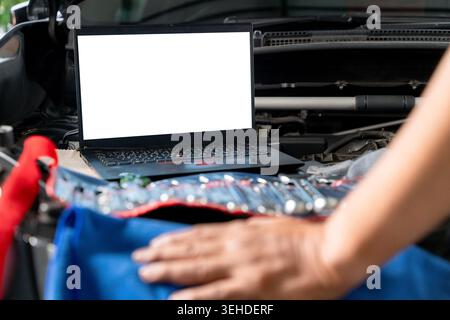 A laptop computer sits on a vehicle's engine block during a computer-aided diagnostic check. Stock Photo