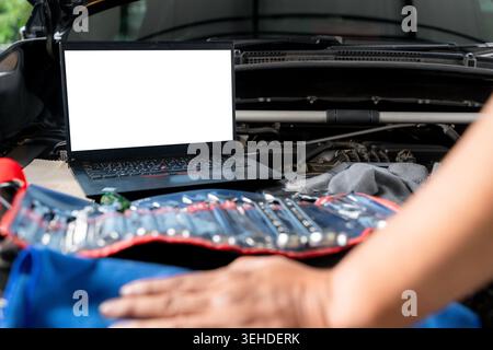 A laptop computer sits on a vehicle's engine block during a computer-aided diagnostic check. Stock Photo