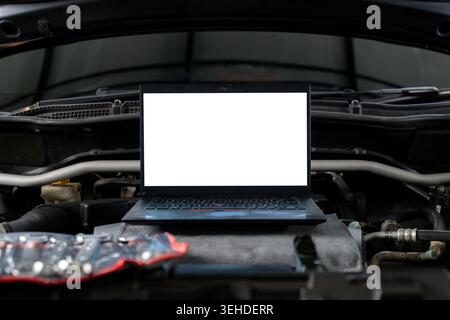 A laptop computer sits on a vehicle's engine block during a computer-aided diagnostic check. Stock Photo