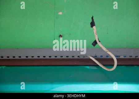 Exposed Electrical Cable Hanging From Ceiling With Damaged Roof Interior and Unsafe Wiring Condition Stock Photo