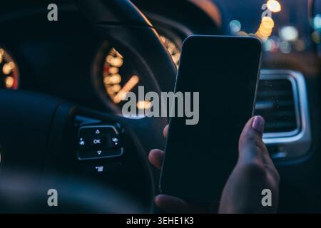 Scam message appears on a phone while driving at night on a busy street Stock Photo