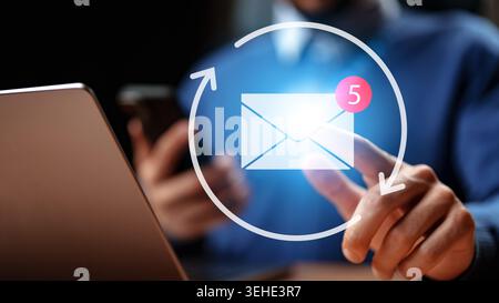 Checking messages on a laptop and phone with notifications showing new emails and updates Stock Photo