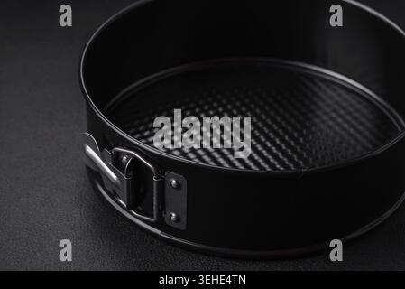 Food, Round metal black detachable baking dish for baking on a dark concrete background Stock Photo