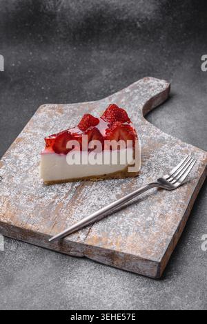 Food, Delicious fresh cheesecake with strawberries, syrup and mascarpone cheese on a textured concrete background Stock Photo