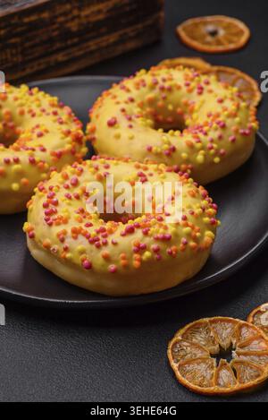 Food, Delicious fresh donuts in yellow glaze with lemon flavor filling on textured concrete background Stock Photo