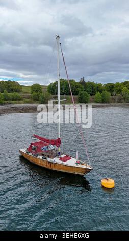 A solitary sailboat resting on calm Scottish waters beneath dramatic skies, where silence and adventure meet Stock Photo