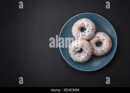 Food, Delicious fresh donut of white or beige color with silver beads and cream on a dark concrete background Stock Photo