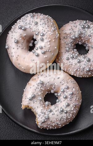 Food, Delicious fresh donut of white or beige color with silver beads and cream on a dark concrete background Stock Photo