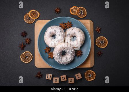 Food, Delicious fresh donut of white or beige color with silver beads and cream on a dark concrete background Stock Photo