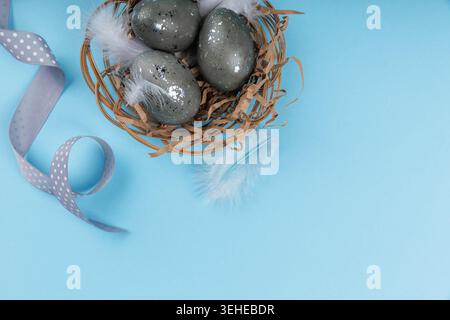 Top view Easter eggs nest with ribbon on blue background Stock Photo