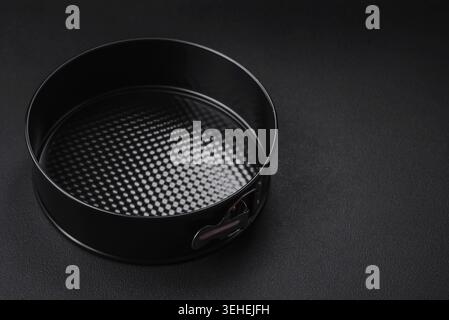 Food, Round metal black detachable baking dish for baking on a dark concrete background Stock Photo
