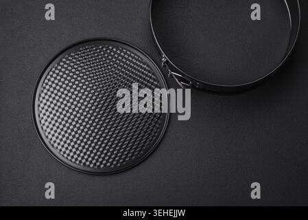 Food, Round metal black detachable baking dish for baking on a dark concrete background Stock Photo