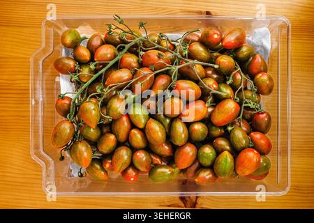 Ripe cherry tomatoes in plastic container with vine Stock Photo