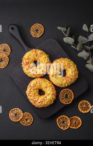 Food, Delicious fresh donuts in yellow glaze with lemon flavor filling on textured concrete background Stock Photo