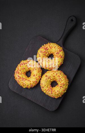 Food, Delicious fresh donuts in yellow glaze with lemon flavor filling on textured concrete background Stock Photo