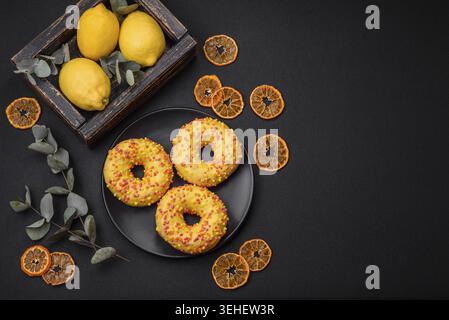 Food, Delicious fresh donuts in yellow glaze with lemon flavor filling on textured concrete background Stock Photo