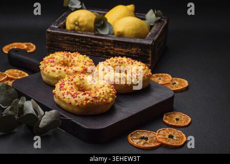 Food, Delicious fresh donuts in yellow glaze with lemon flavor filling on textured concrete background Stock Photo