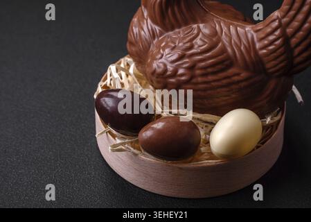 Food, Chocolate Easter hen and eggs in a nest with straw on a dark background. Easter preparations Stock Photo