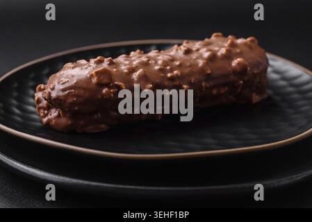 Food, Delicious fresh eclair cake or profiterole with chocolate and nuts on a dark concrete background Stock Photo