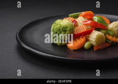 Food, Delicious juicy broccoli vegetables, carrots, asparagus beans, bell peppers steamed in a black plate on a dark concrete background Stock Photo